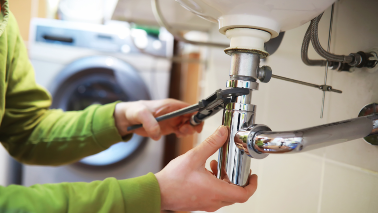 Pipe repair service in Melbourne, Victoria, with a plumber tightening and reconnecting the drain pipe beneath a residential sink.