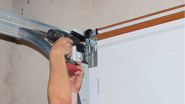 Garage door installation service in Carlton, Victoria, with a technician securing the track and mounting hardware on a residential sectional door.