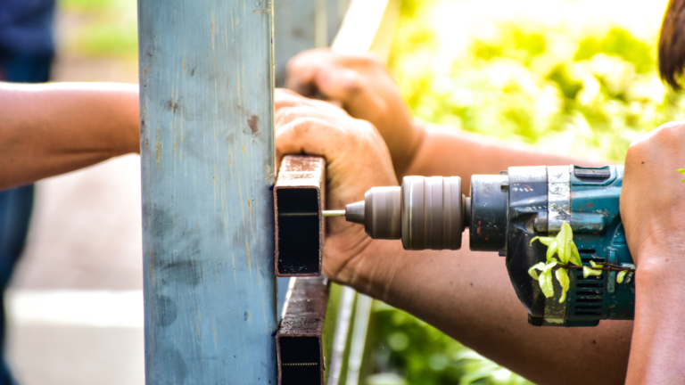 Fence repair service in Collingwood, Melbourne, with a tradesperson drilling and securing metal fence components.